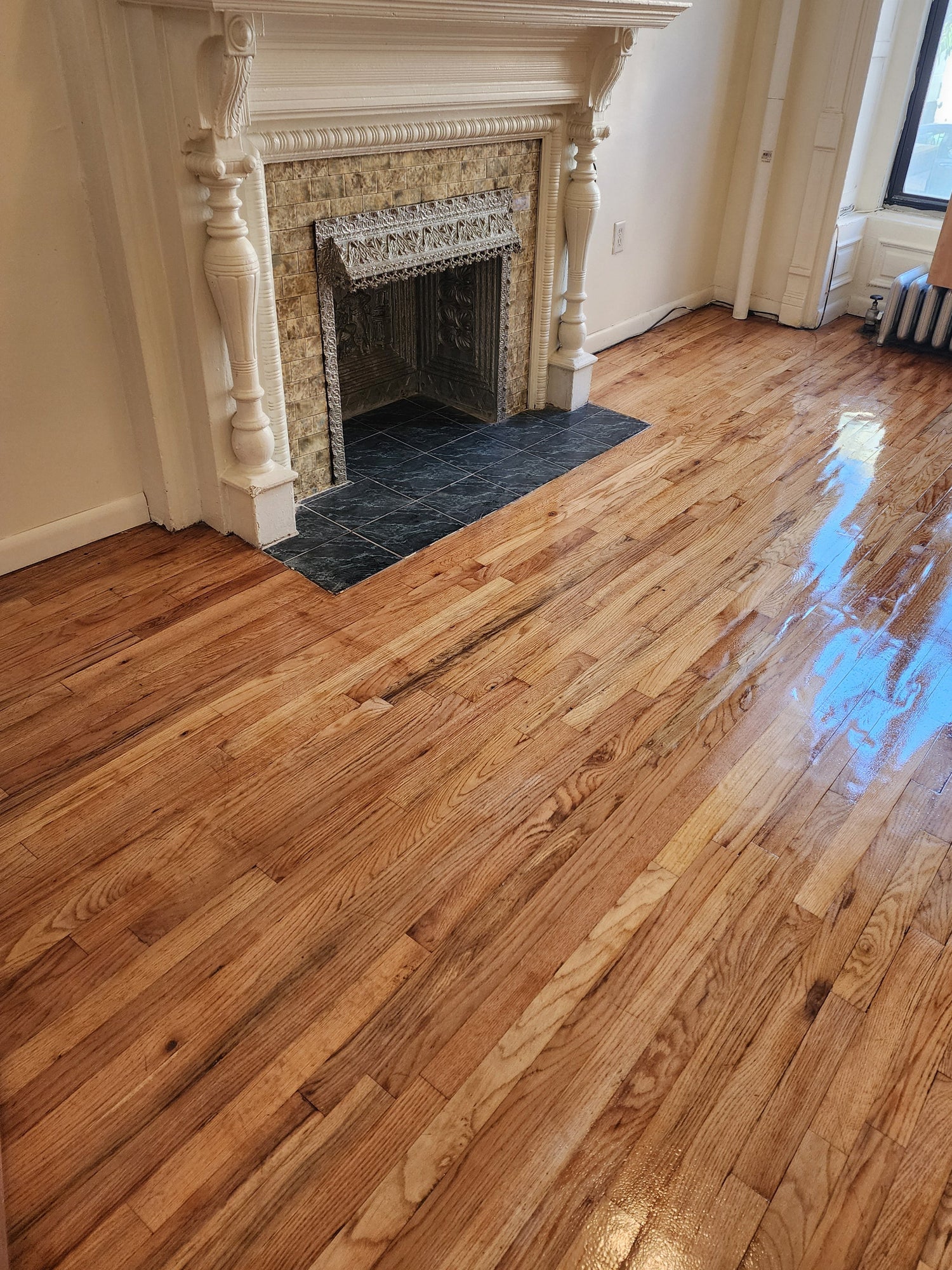 Wooden floor with a decorative fireplace in a room with large windows.